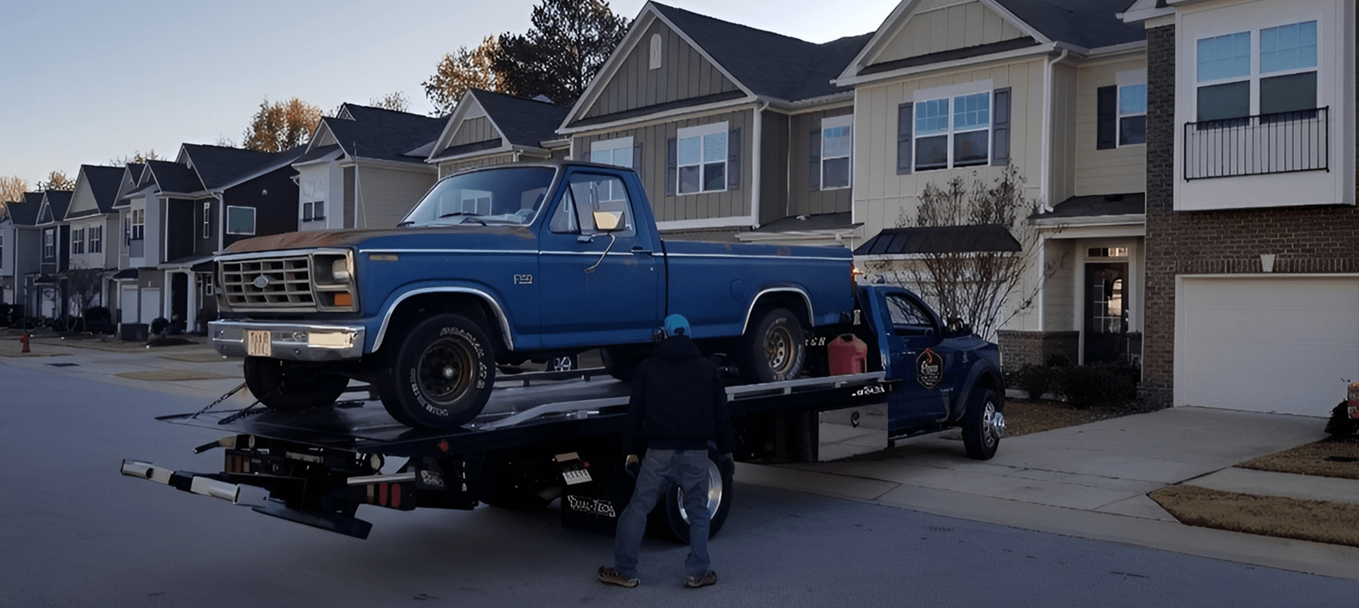 Tow truck transporting vintage blue pickup